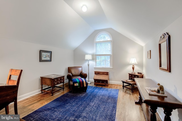 living area featuring lofted ceiling, wood finished floors, and baseboards