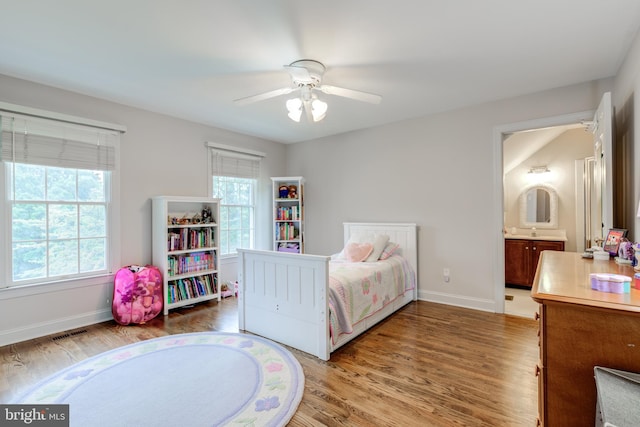 bedroom featuring wood finished floors, baseboards, a sink, ceiling fan, and connected bathroom
