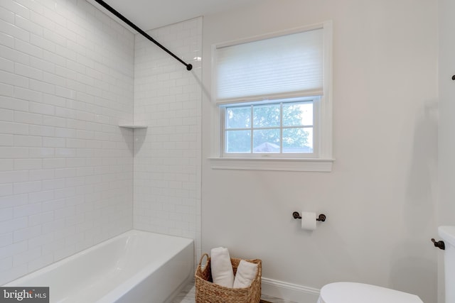 bathroom with toilet, shower / bathtub combination, and baseboards