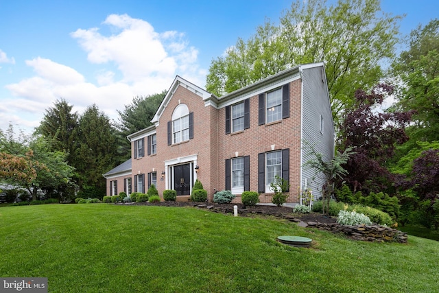 colonial house featuring a front lawn and brick siding