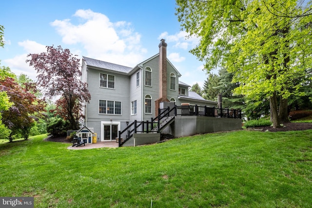 rear view of house with stairs, a chimney, a patio area, a wooden deck, and a yard
