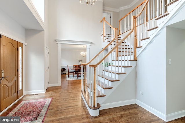 foyer featuring a chandelier, stairway, wood finished floors, baseboards, and a high ceiling