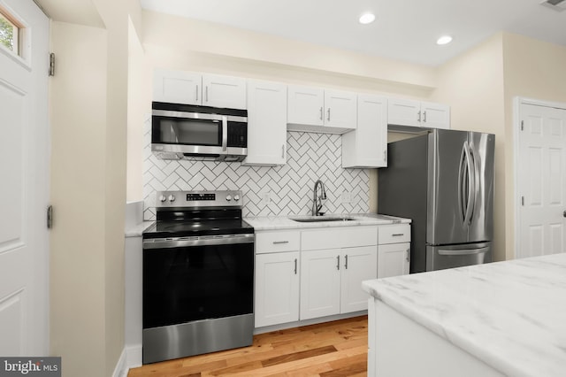 3827 Boarman Ave, Baltimore, MD 21215 - kitchen featuring appliances with stainless steel finishes, a sink, tasteful backsplash, light wood-style flooring, and light stone counters