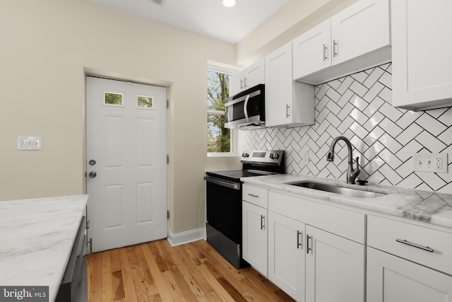 3827 Boarman Ave, Baltimore, MD 21215 - kitchen with stainless steel appliances, a sink, tasteful backsplash, white cabinets, and light wood finished floors