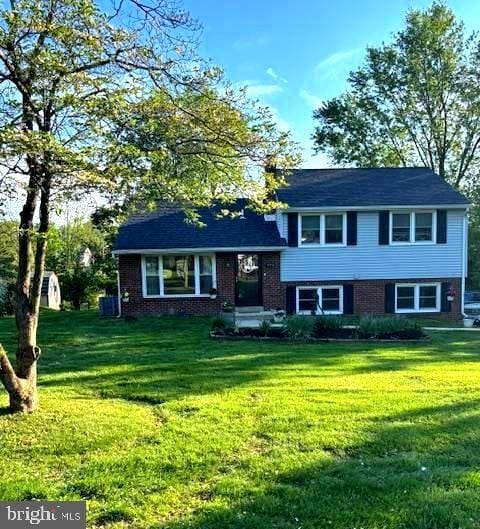 tri-level home featuring a front yard and brick siding