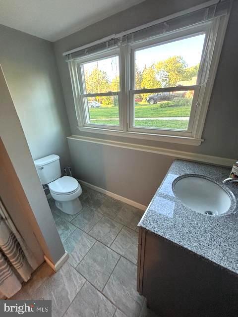 bathroom featuring toilet, baseboards, and vanity