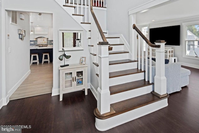 staircase featuring wood finished floors and baseboards