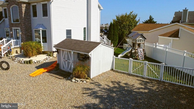 view of property exterior featuring a playground, a shed, a fenced backyard, and an outbuilding