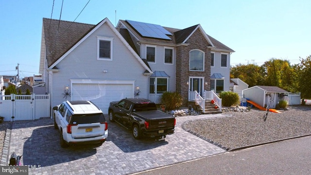 view of front of property with a gate, a storage shed, solar panels, a garage, and driveway