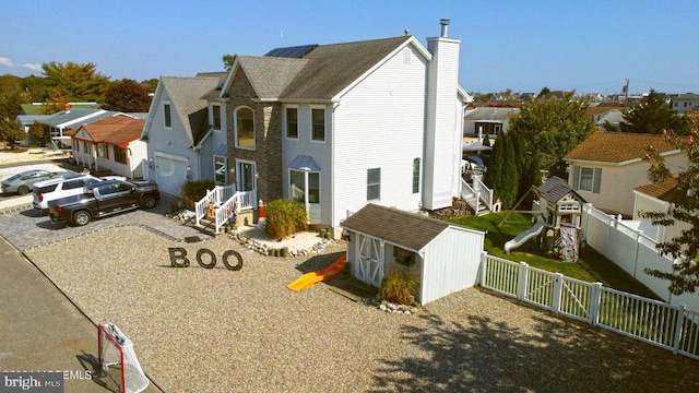 view of front of property featuring a storage unit, a chimney, a residential view, and fence