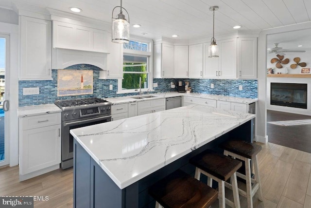 kitchen with stainless steel appliances, a sink, light wood-style flooring, white cabinets, and a kitchen breakfast bar