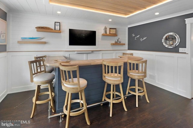 bar area with a decorative wall, wooden ceiling, recessed lighting, and dark wood-style floors