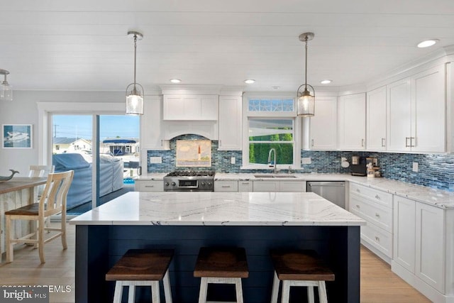 kitchen with a sink, stainless steel appliances, a kitchen breakfast bar, white cabinetry, and recessed lighting