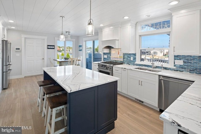 kitchen with appliances with stainless steel finishes, a sink, a center island, white cabinetry, and recessed lighting