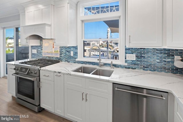 kitchen featuring appliances with stainless steel finishes, a sink, decorative backsplash, and white cabinets