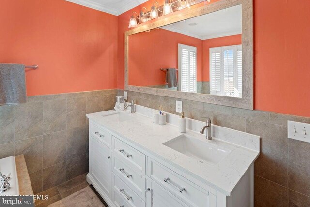 bathroom featuring tile walls, crown molding, wainscoting, and double vanity