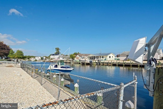 dock area featuring a water view, fence, and a residential view