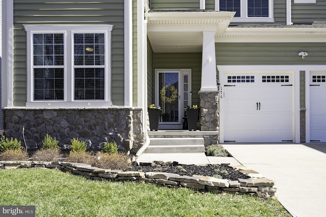 view of exterior entry featuring stone siding, driveway, and an attached garage