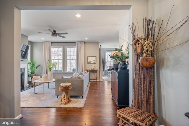 living room featuring dark wood-style floors, a glass covered fireplace, a ceiling fan, and recessed lighting