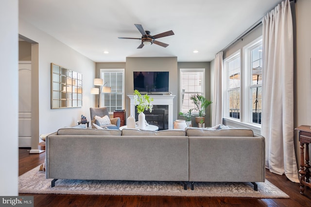 living room with a ceiling fan, a glass covered fireplace, dark wood-style flooring, and recessed lighting