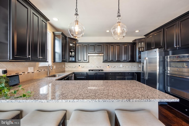kitchen featuring a sink, stainless steel appliances, glass insert cabinets, decorative backsplash, and recessed lighting