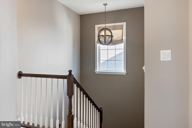 stairs featuring a chandelier