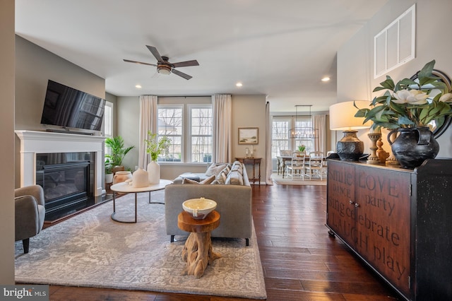 living room with a ceiling fan, dark wood-type flooring, recessed lighting, and a glass covered fireplace