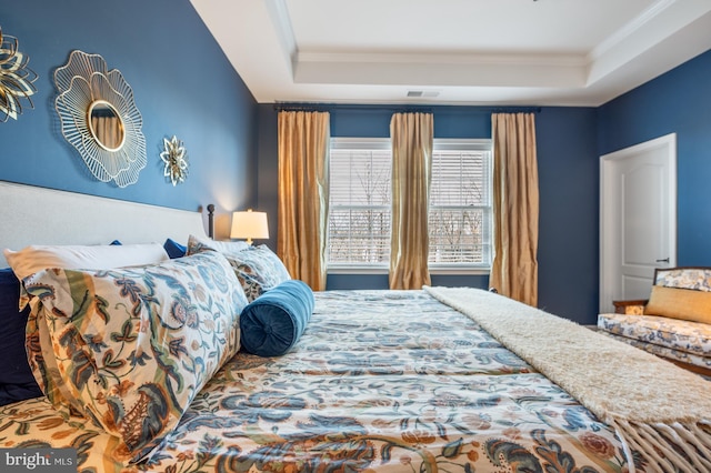 bedroom with a raised ceiling and crown molding