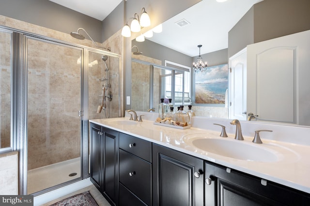 full bath with a stall shower, double vanity, and a chandelier