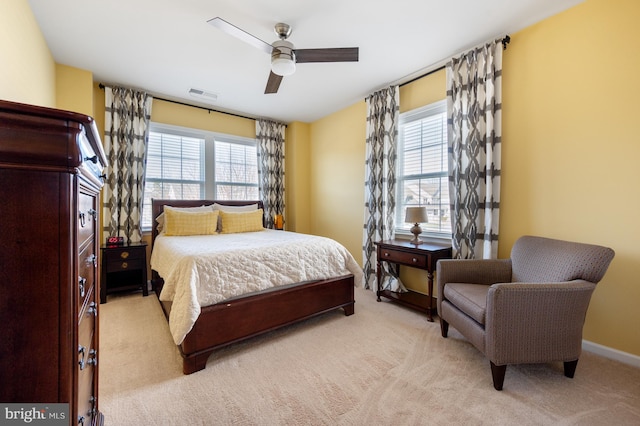 bedroom featuring multiple windows, light carpet, and a ceiling fan