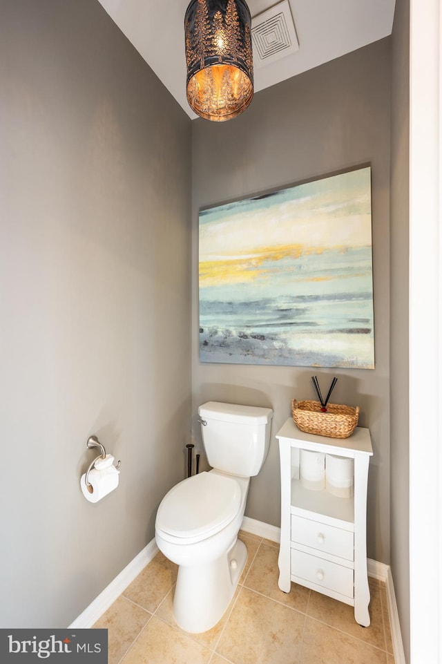 half bathroom with tile patterned floors, toilet, and baseboards