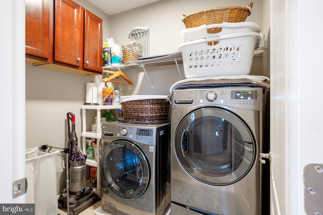 clothes washing area with washer and clothes dryer and cabinet space