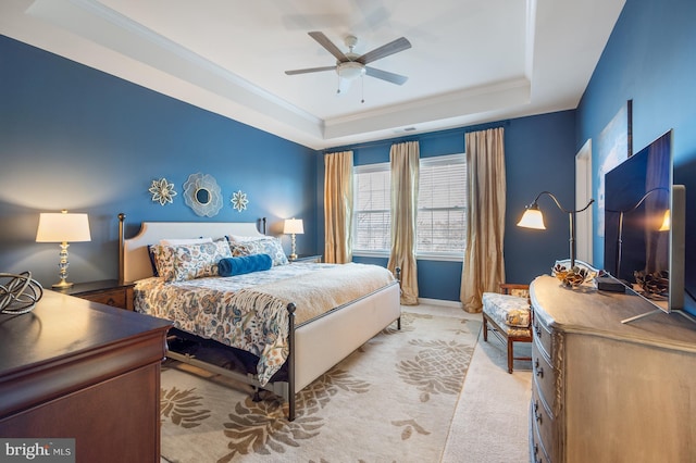bedroom with a tray ceiling, light colored carpet, ceiling fan, and ornamental molding