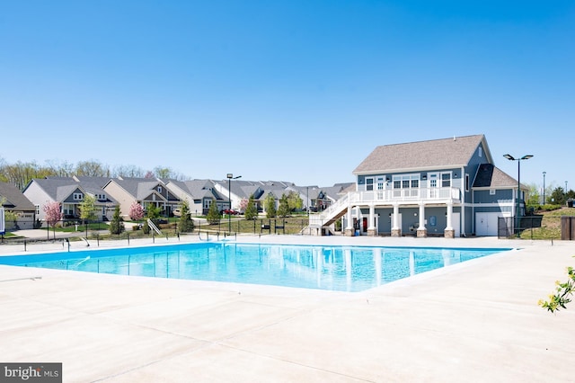 community pool featuring fence, stairway, a residential view, and a patio area