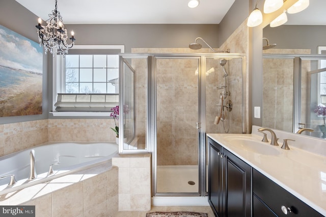bathroom with a shower stall, a chandelier, vanity, and a garden tub