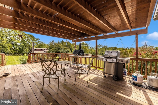 wooden deck with area for grilling, view of scattered trees, and a lawn