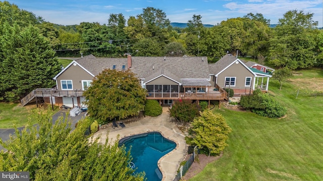 back of house with a deck, stairs, a lawn, an outdoor pool, and a sunroom