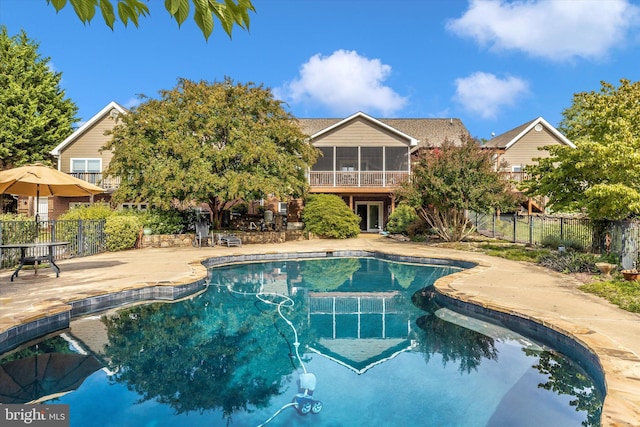 outdoor pool featuring a patio, fence, and a sunroom