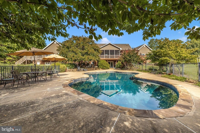 view of swimming pool with fence, a patio, and a sunroom