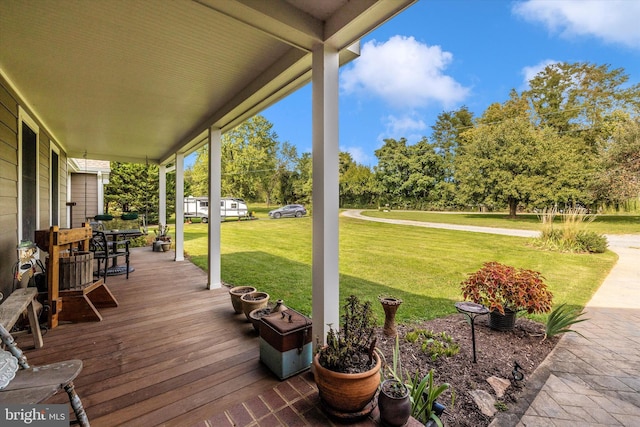 wooden terrace with a porch, a yard, and view of wooded area