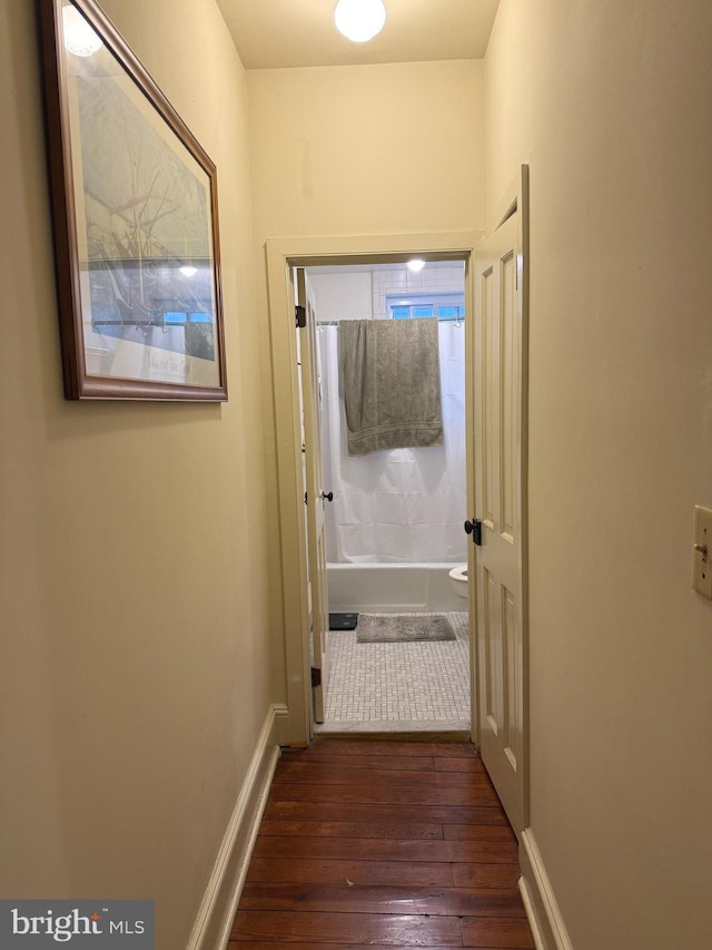 hall featuring dark wood-type flooring and baseboards