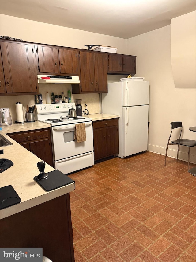 kitchen with white appliances, under cabinet range hood, light countertops, and dark brown cabinetry