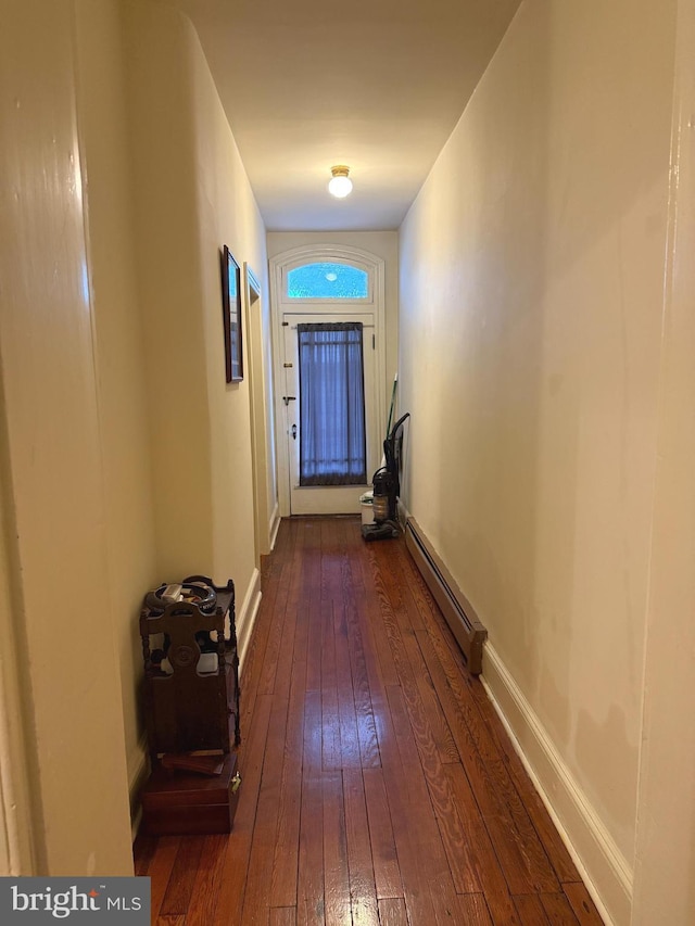 hallway featuring baseboard heating, dark wood finished floors, and baseboards