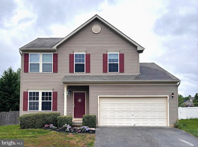 traditional home featuring fence and asphalt driveway