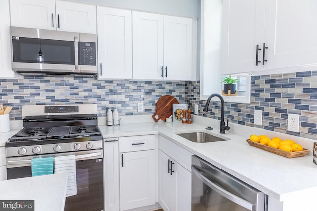 kitchen featuring stainless steel appliances, a sink, white cabinetry, light stone counters, and backsplash