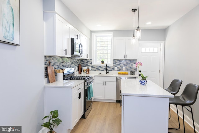 kitchen with appliances with stainless steel finishes, a sink, a kitchen bar, a center island, and tasteful backsplash