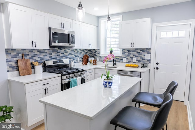 kitchen featuring stainless steel appliances, a sink, a kitchen bar, white cabinets, and recessed lighting