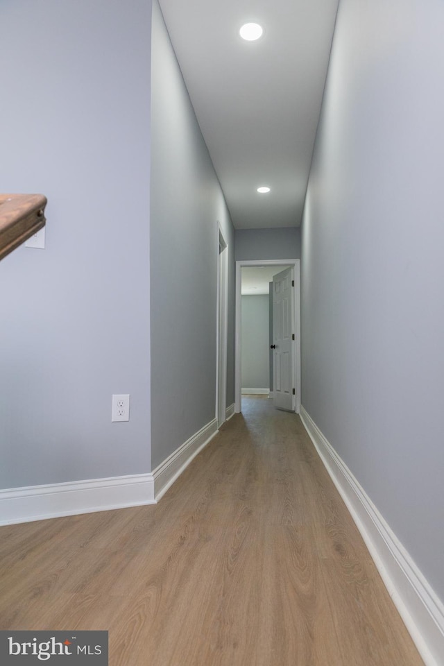hallway with light wood-type flooring, baseboards, and recessed lighting