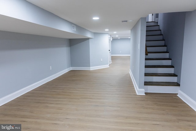 finished below grade area featuring stairs, baseboards, recessed lighting, and wood finished floors