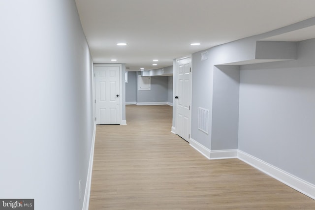 corridor featuring baseboards, light wood finished floors, and recessed lighting